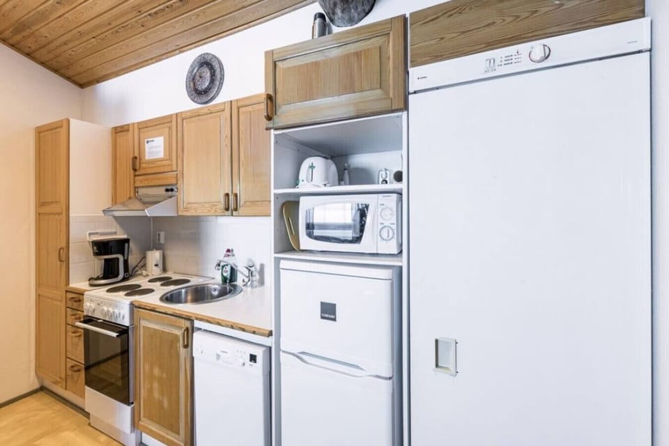 Kitchen with an electric stove, microwave, kettle, dishwasher and a fridge with freezer.