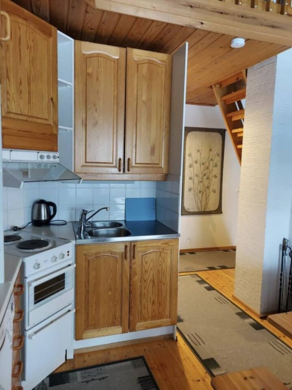 Kitchen corner with an electric stove, sink and plenty of cabinet storage.