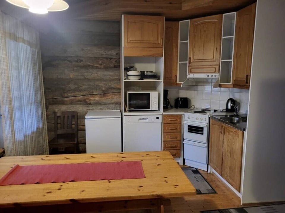 Kitchen equipped with an electric stove and oven, microwave, refrigerator and electric kettle.