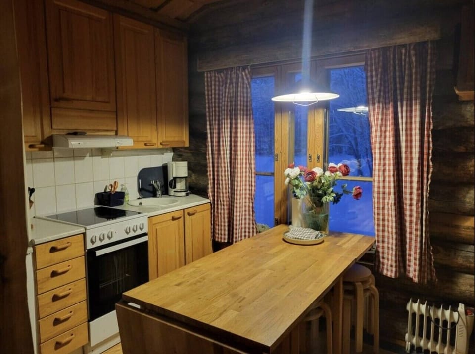 Separate kitchen with an oven, coffee maker and a solid wooden dining table.