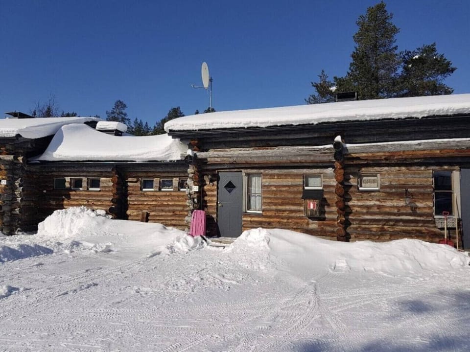 Snow-covered log building with the private entrance to the apartment.
