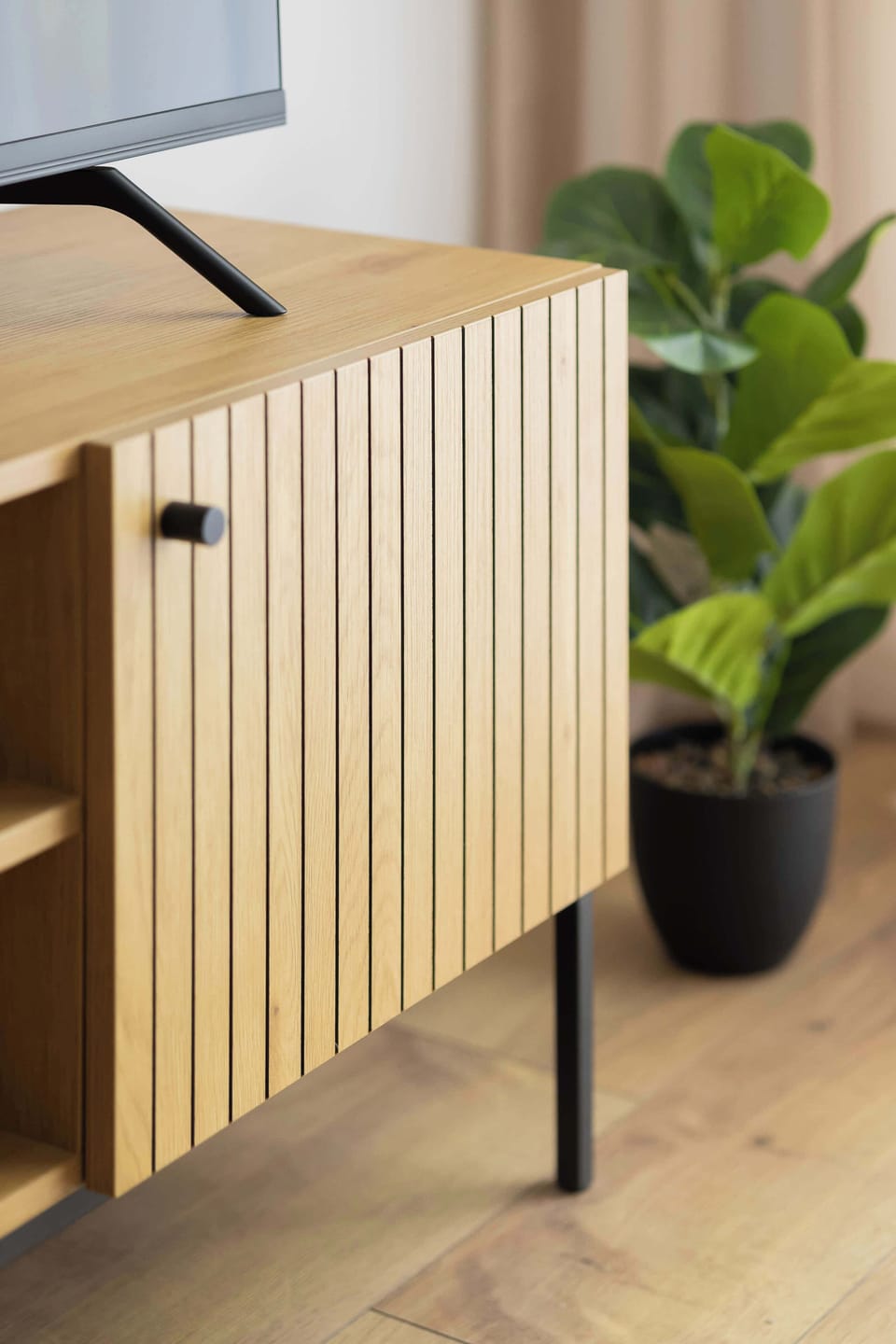 Modern living room corner with a wooden decorative partition, a green plant and a comfortable seating area.
