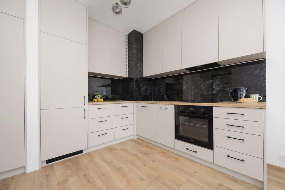 Modern kitchenette with cabinets, countertop and backsplash, a built-in oven, a sink and plenty of storage space.