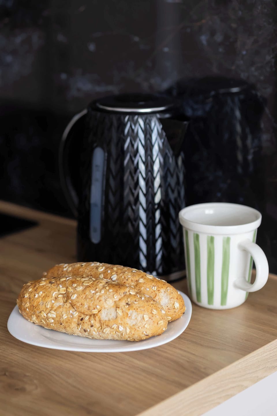 Close-up of a cup of coffee and a pastry placed on a small table, with a black coffee machine in the background.