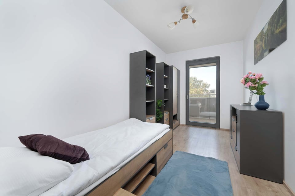 Cozy bedroom with a single bed, a bedside table, a wardrobe and large window.