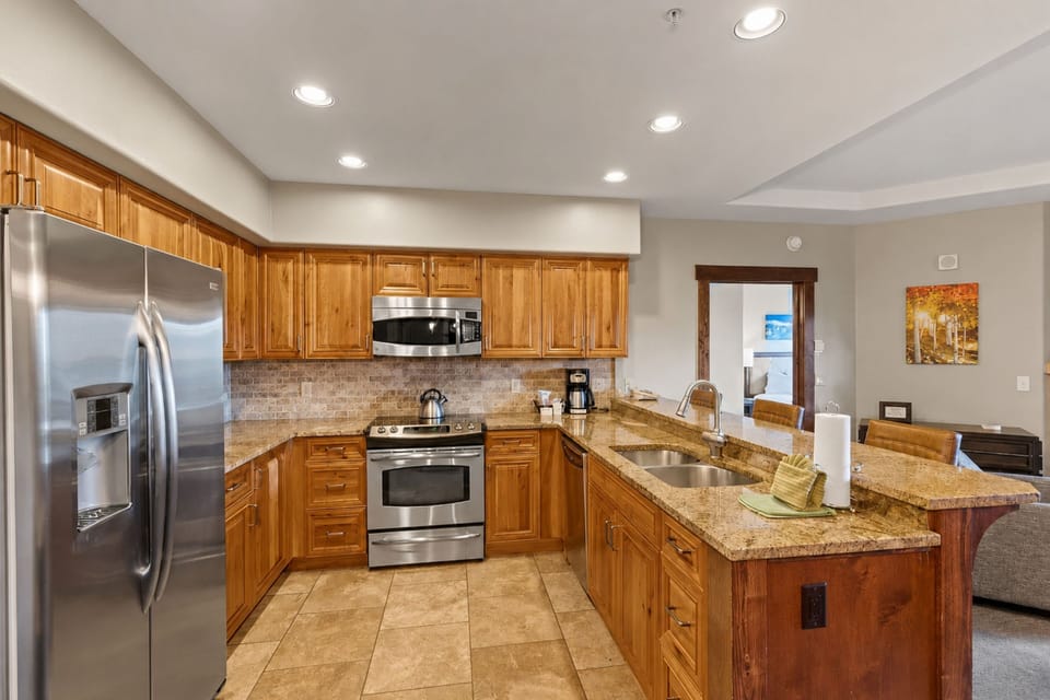 Your fully equipped kitchen awaits with gleaming granite counters, warm wood cabinetry, and stainless steel appliances—everything you need to whip up your favorite meals in style.