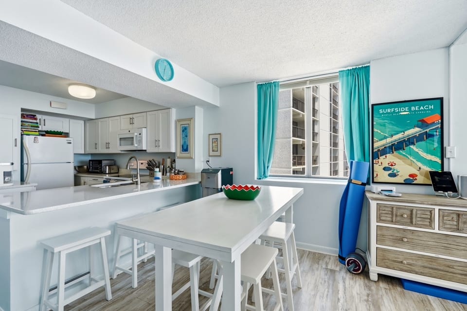 Gather for meals in your bright kitchen-dining space with cheerful coastal accents, fresh ocean breezes from the window, and a fully equipped kitchen ready for your favorite recipes.