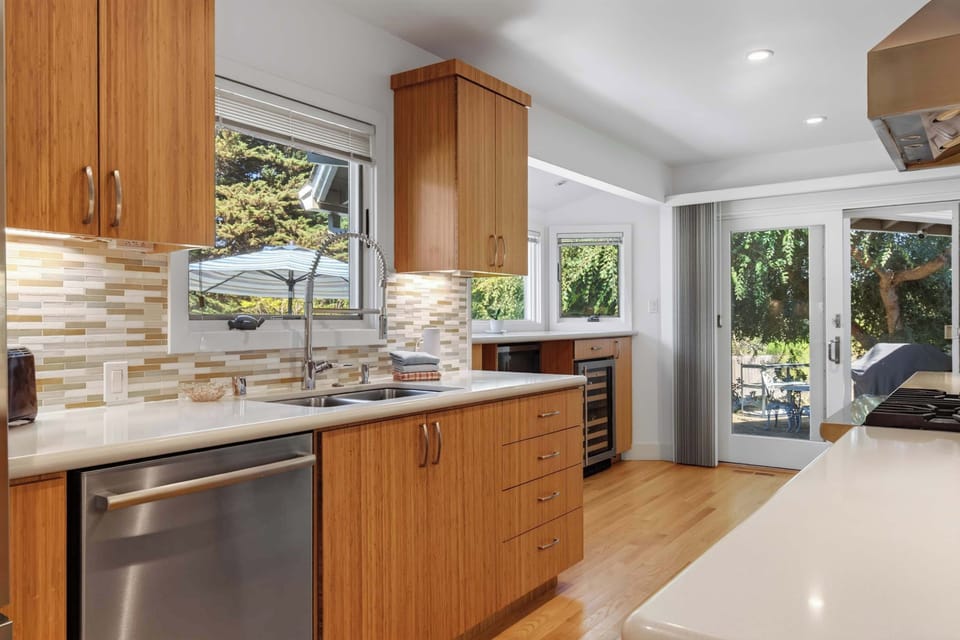 Prep dinner at the quartz counters while mosaic tile glows under cabinet lights and the window looks straight out to the patio grill.