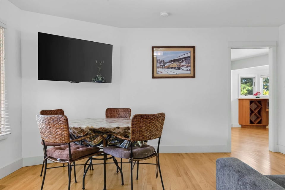 Square dining table, metal-frame chairs, and wall-mounted TV make this corner work for meals, board games, or casual hangouts.