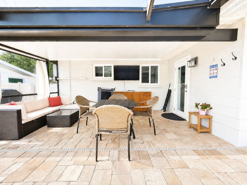 Covered patio with outdoor dining, lounge seating, and TV