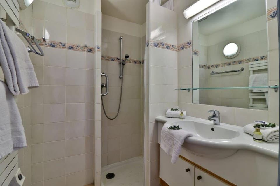 Small bathroom with a shower, mirror, and sink.