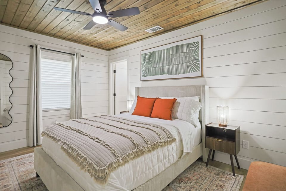 Cozy modern bedroom with wood ceiling, plush bed, and warm designer touches