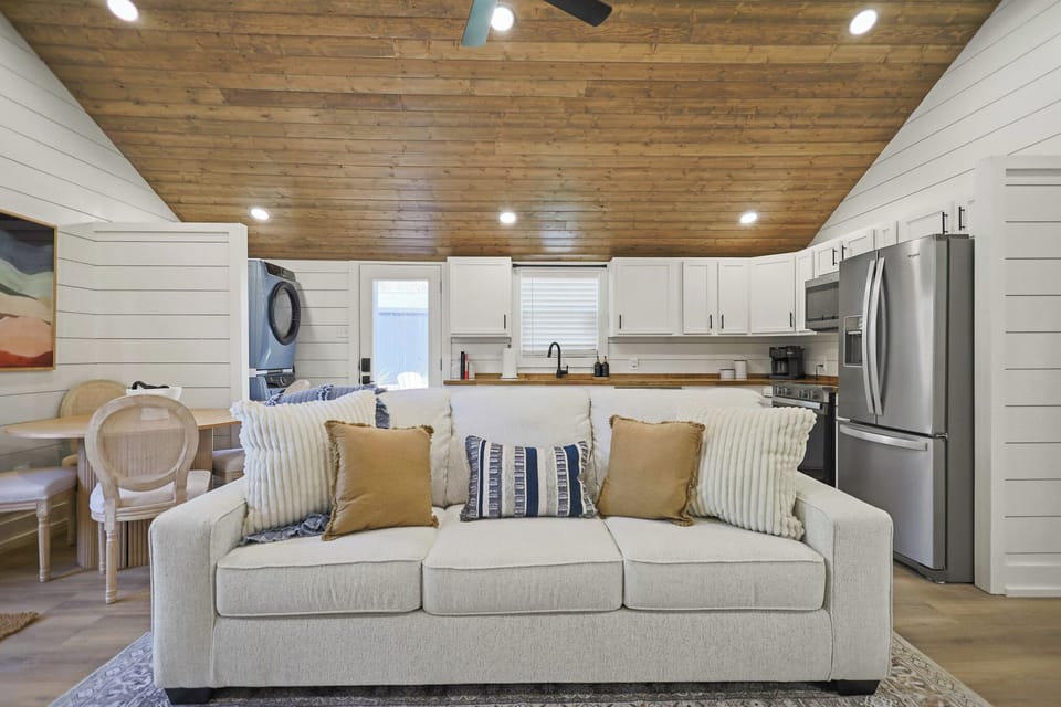 Bright farmhouse-style living room with open kitchen and warm wood ceilings
