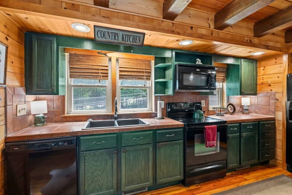 A warm, cabin‑style kitchen with a double‑door fridge, dishwasher, microwave, and a spacious bar area—perfect for gathering after long days at TIEC or exploring the mountains.