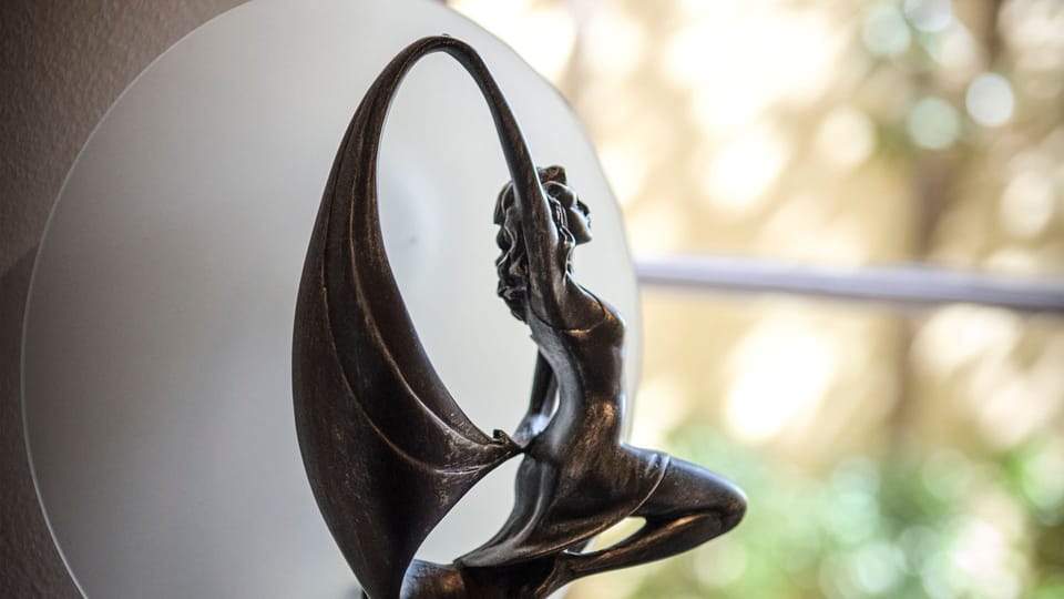 Artistic figurine decor piece with a soft-focus outdoor background.