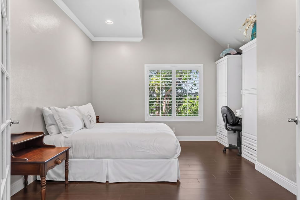 Another view of the inviting guest room, featuring vaulted ceilings and plantation shutters.