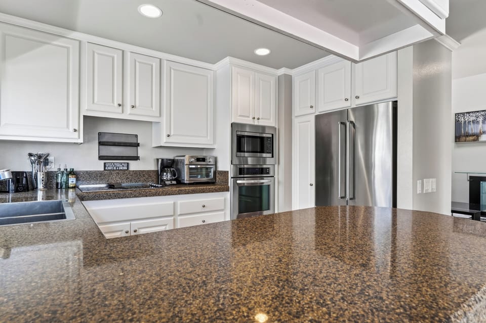 The bright kitchen features abundant cabinetry, stainless steel appliances, and a spacious island.
