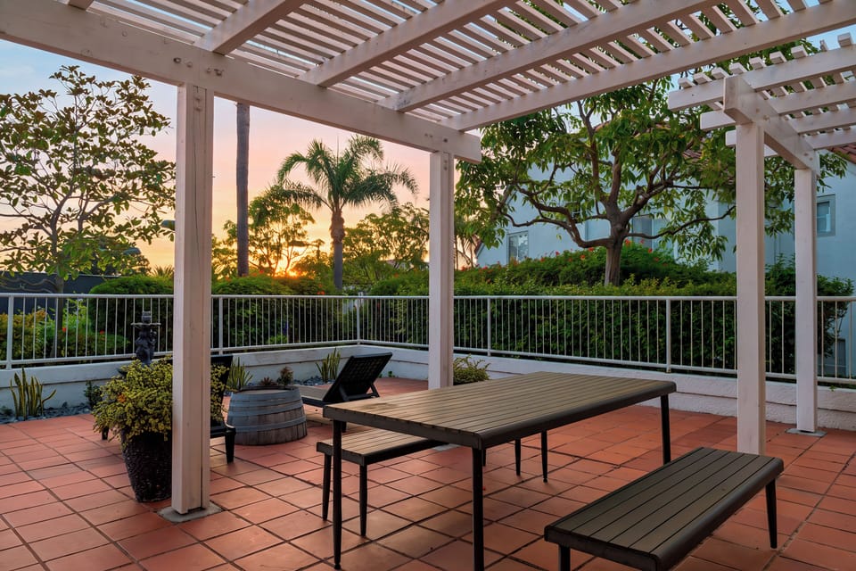 The pergola-covered dining area offers a beautiful setting for sunset meals outdoors.