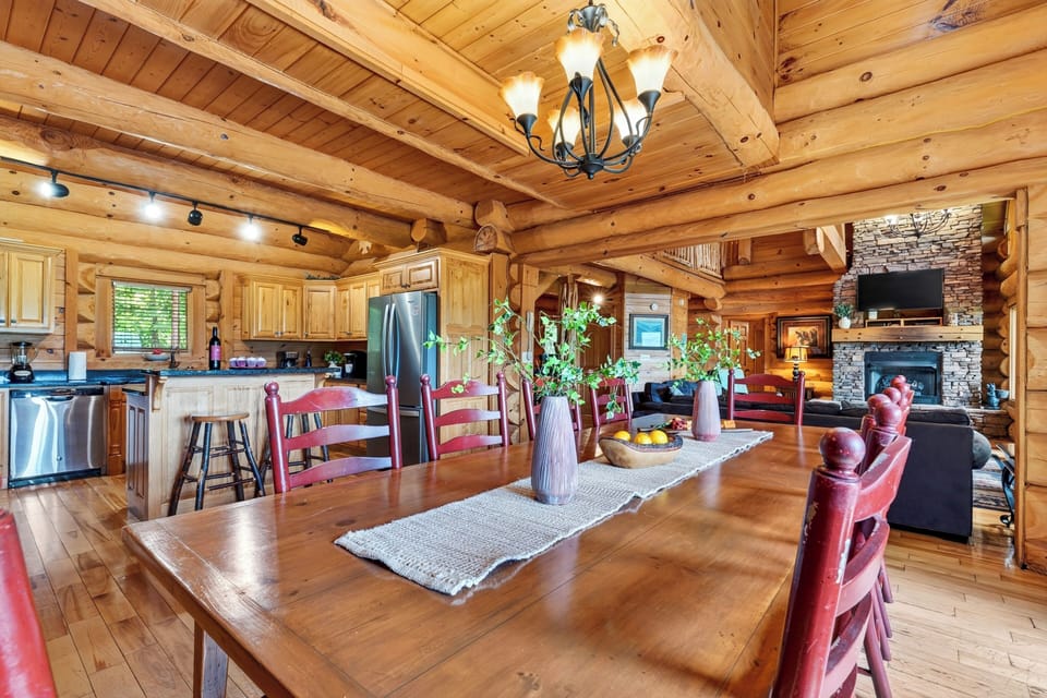 Gather around the spacious dining table for shared meals, with warm log-cabin character and mountain views just beyond the doors.