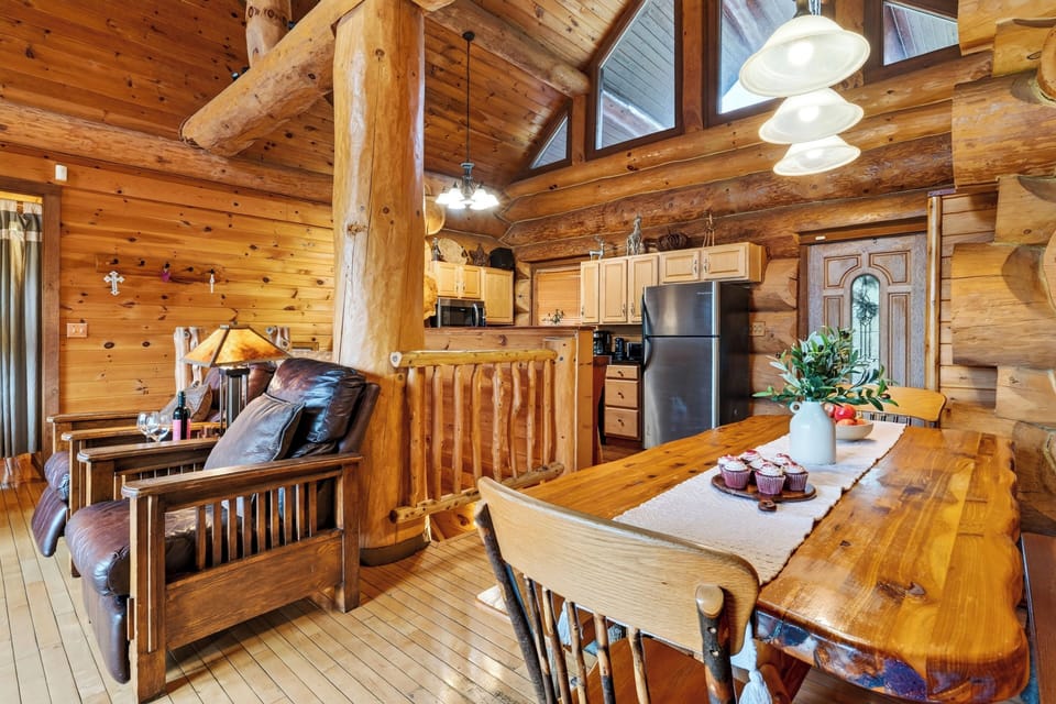 Wood dining table beside the open kitchen and living area.