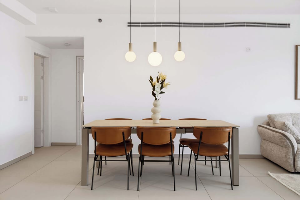 Enjoy group meals around a light wood dining table underneath chic pendant lights in this space.