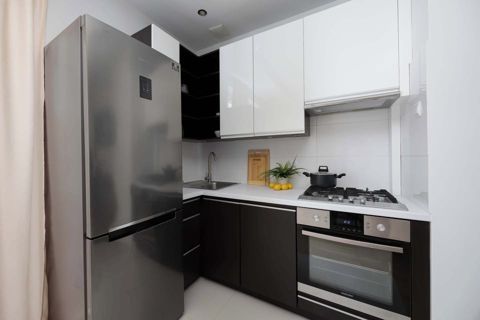 Modern kitchenette equipped with sleek dark cabinets, white upper cupboards, and built-in appliances.
