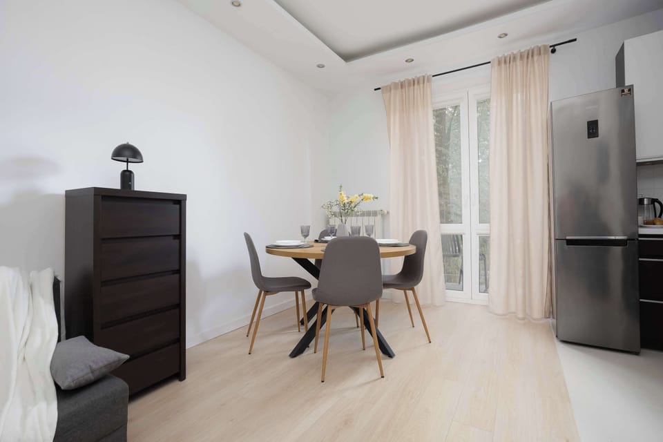 Bright living room with a dining area, elegant furniture, and large windows with light curtains.