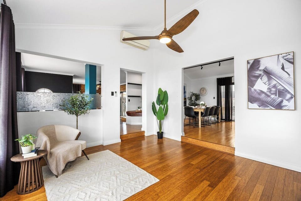 Unwind in this bright living area featuring high ceilings, a cooling ceiling fan, air conditioning, and a cozy reading armchair.