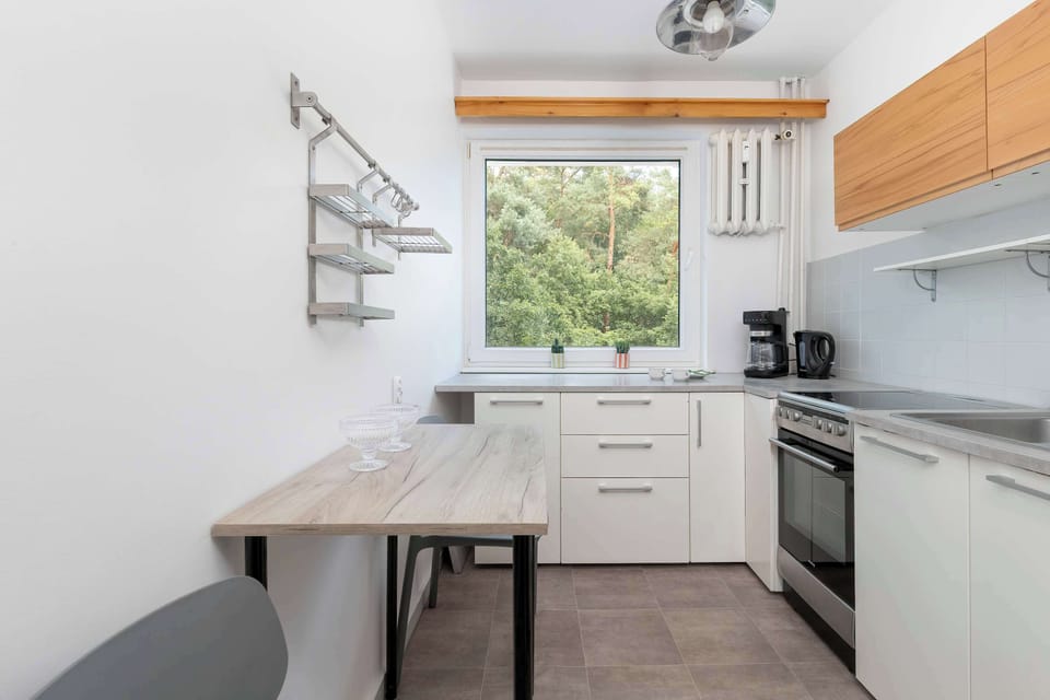A practical kitchen setup includes a small table extending from the wall. Utensils hang neatly from a wall-mounted rack above the counter.
