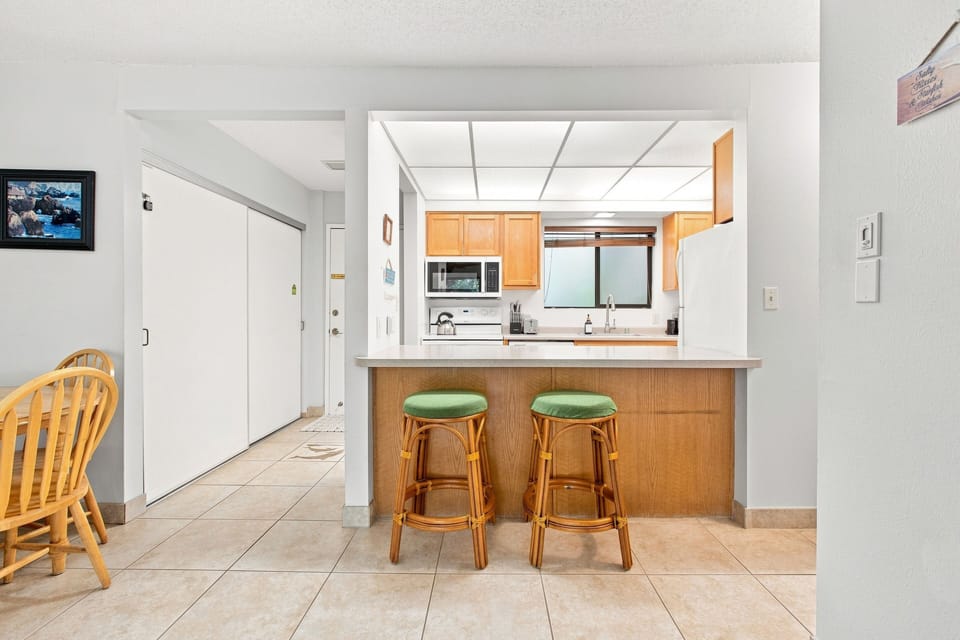 Your open-concept kitchen invites easy living with a convenient breakfast bar, warm wood cabinetry, and bright natural light streaming through the window above the sink.