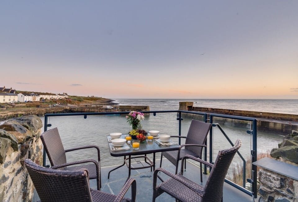 Majestic private balcony overlooking Craster Harbour, with outdoor seating for enjoying the spectacular coastal views.