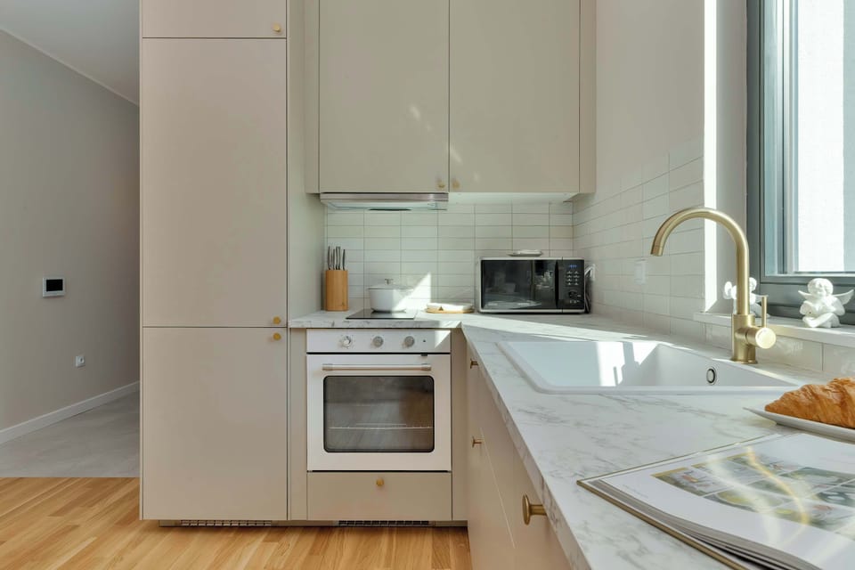 Bright kitchenette with white cabinets, appliances, and a dining area.
