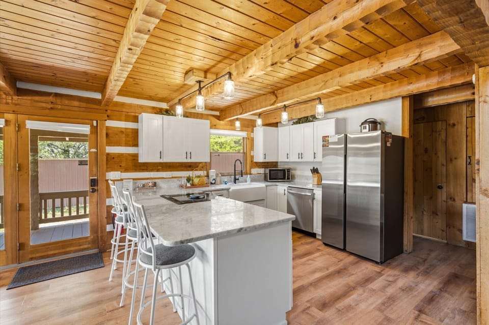Your fully equipped kitchen glows with natural warmth from vaulted wood ceilings and exposed beams. Gather around the spacious island with stainless appliances and modern conveniences at your fingertips.