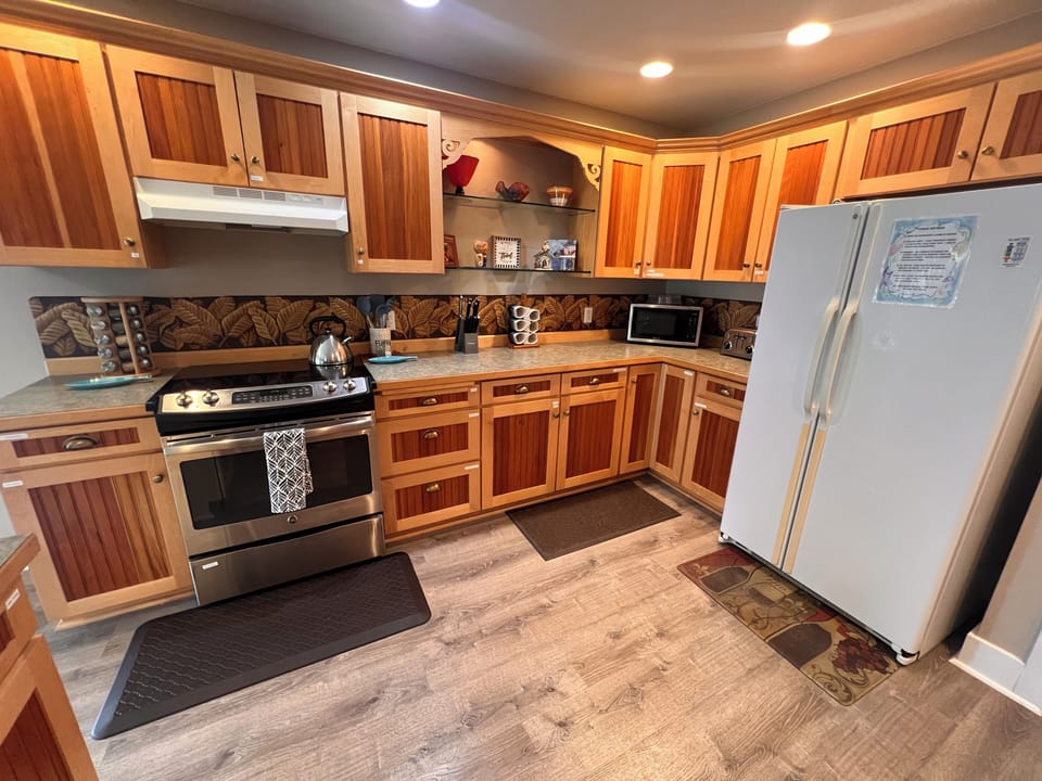 Your fully-equipped kitchen blends rustic elegance with modern convenience, featuring warm wood cabinetry, stainless steel appliances, and custom details perfect for preparing family meals or morning coffee.