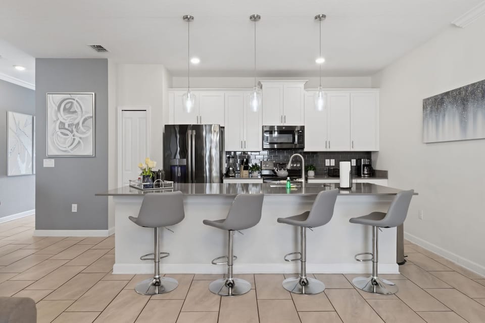 Fully equipped kitchen with a large island, breakfast seating, and stainless-steel appliances.