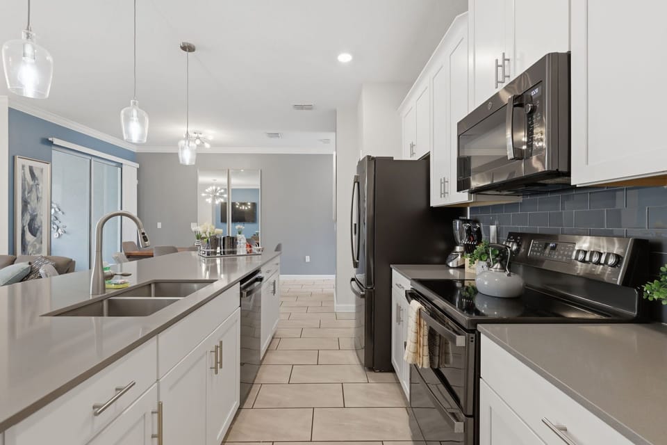 Fully equipped kitchen with a large island, breakfast seating, and stainless-steel appliances.