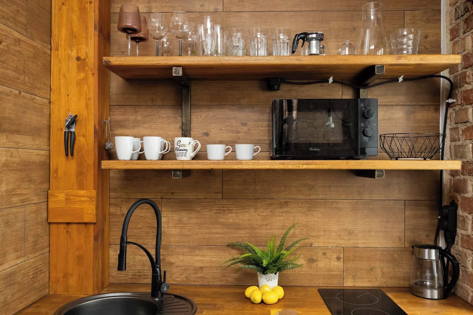 A detailed look at the kitchenette shelves displaying neatly arranged mugs, glasses, and a microwave below. A small plant adds a touch of greenery.