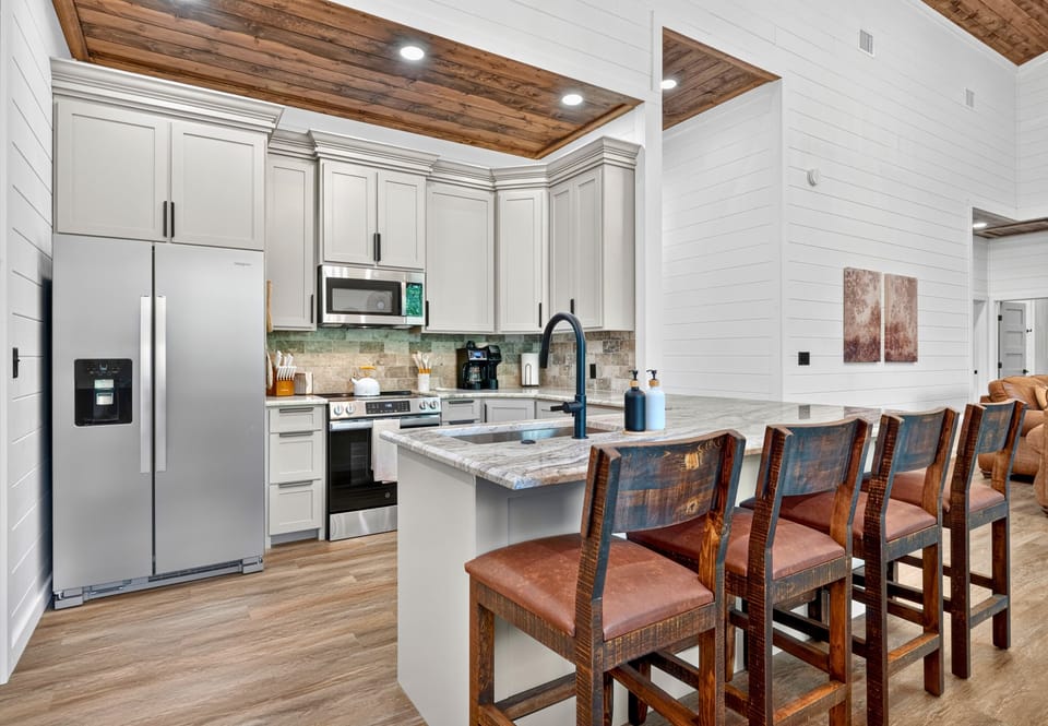 Bright cabinetry, generous counter space, and plenty of seating come together in a kitchen designed to make group meals feel relaxed and easy.