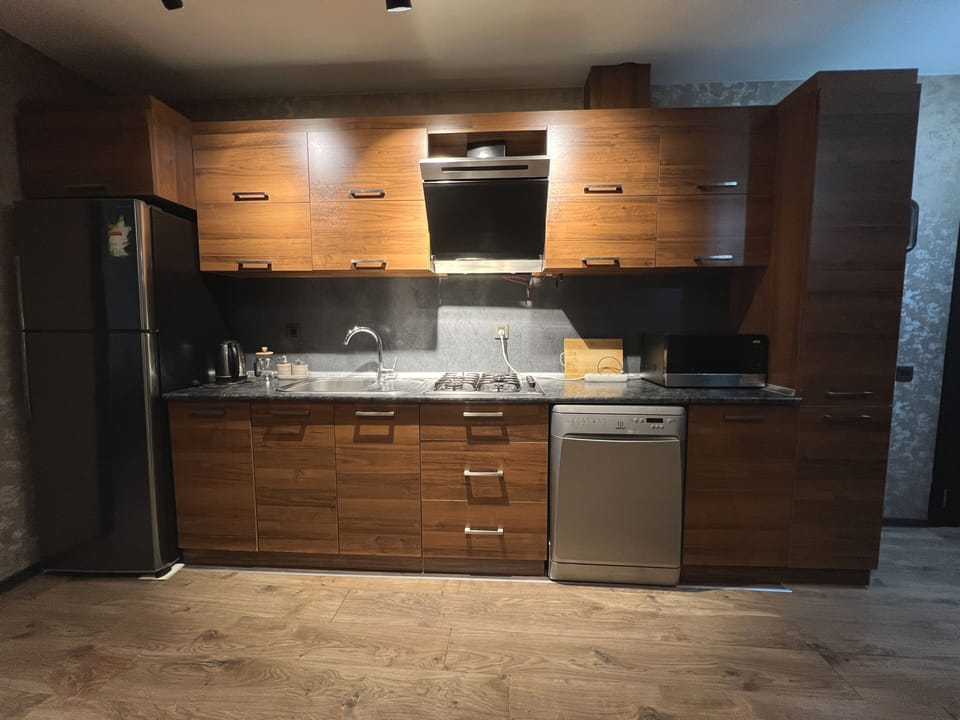 Full kitchen with cabinetry, refrigerator, dishwasher and cooking area.