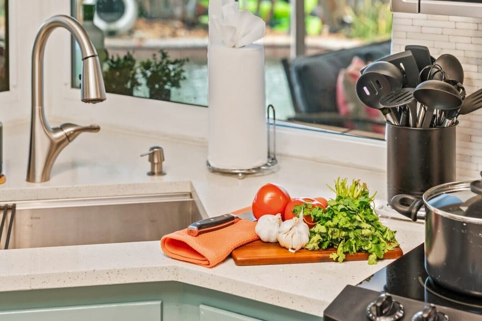 Modern Kitchen & Prep Station: Cook group meals effortlessly in this modern kitchen, highlighting sleek quartz countertops, a deep undermount stainless steel sink with a pull-down sprayer, a smooth glass cooktop, and custom tile backsplash.