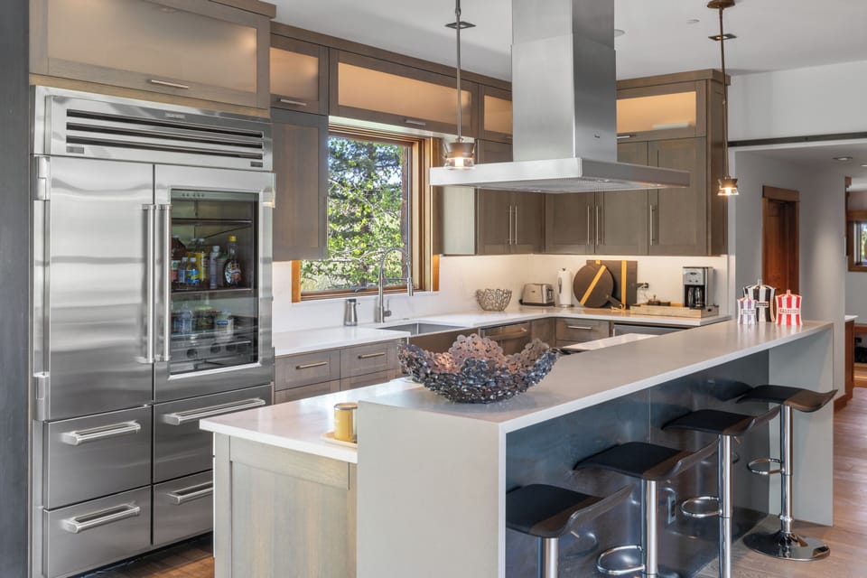 Sleek, modern kitchen with pristine white countertops, natural light, and warm wood accents. Perfect for preparing memorable meals with style and comfort.