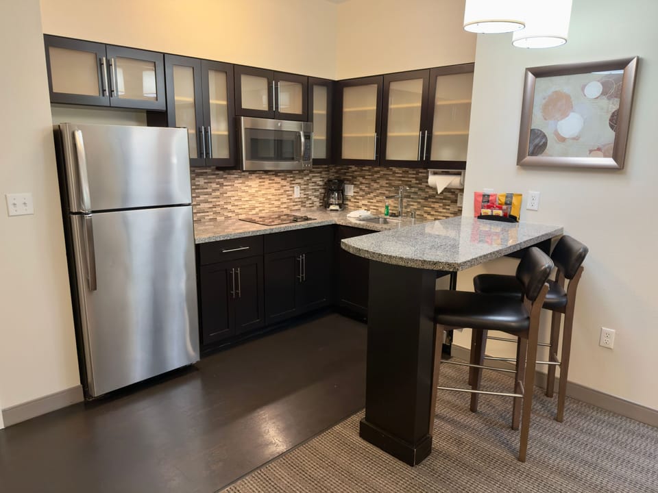 Spacious kitchen featuring a bar area, refrigerator, and decorative wall art.