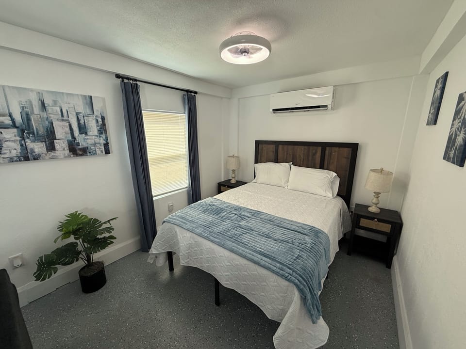 Bright modern bedroom with queen bed, AC, and stylish contemporary decor