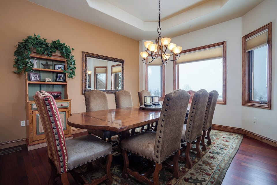 Gather around this elegant dining table where sunlight streams through expansive windows, offering peaceful views while you enjoy memorable meals together in comfort and style.