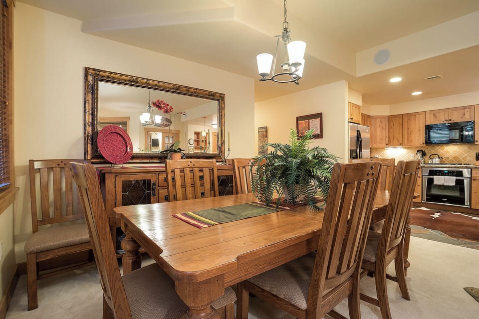 Gather around this spacious dining table where you'll enjoy meals with loved ones under warm lighting, with the fully-equipped kitchen just steps away for your convenience.