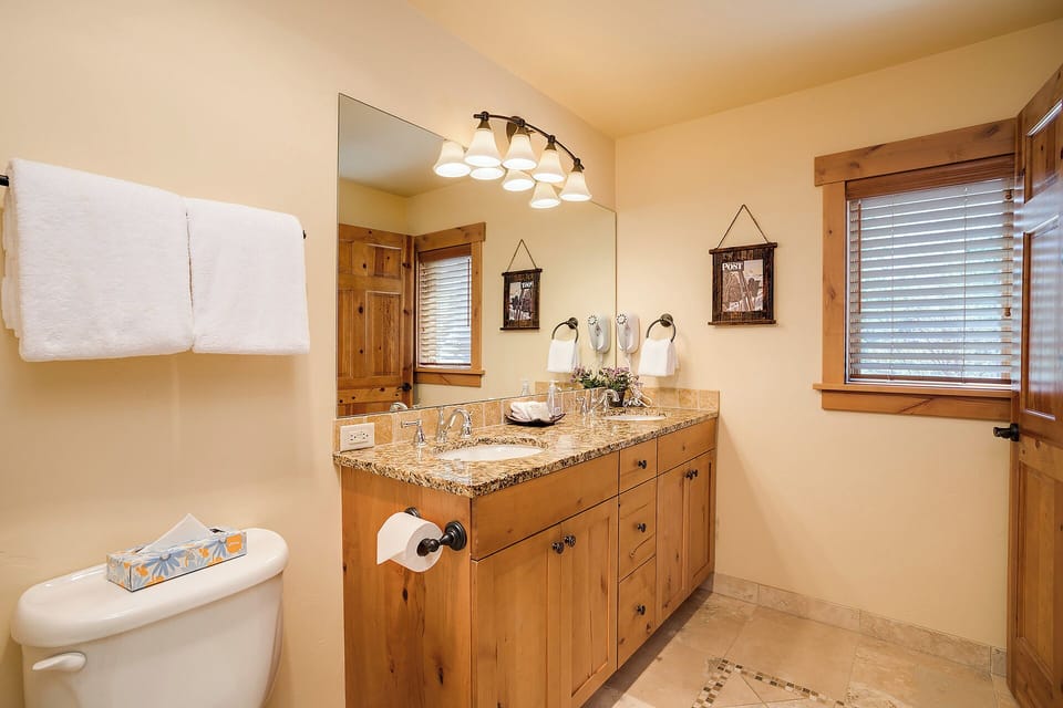 Step into your private bathroom with granite countertops, warm wooden cabinetry, and fresh towels awaiting your arrival. Rustic charm meets modern comfort for your ultimate relaxation.