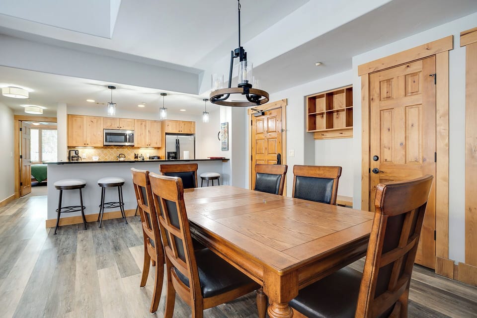 Gather around this inviting dining table, where your group can share meals and stories after a day of adventure. The open layout flows into the fully equipped kitchen, making it easy to cook and connect.