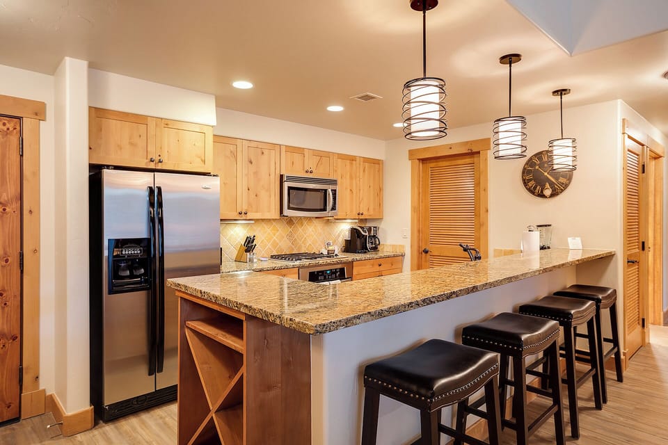 Your fully-equipped gourmet kitchen invites you to craft memorable meals at the spacious granite island, with modern stainless appliances, warm wood cabinetry, and stylish pendant lighting creating a welcoming culinary haven.