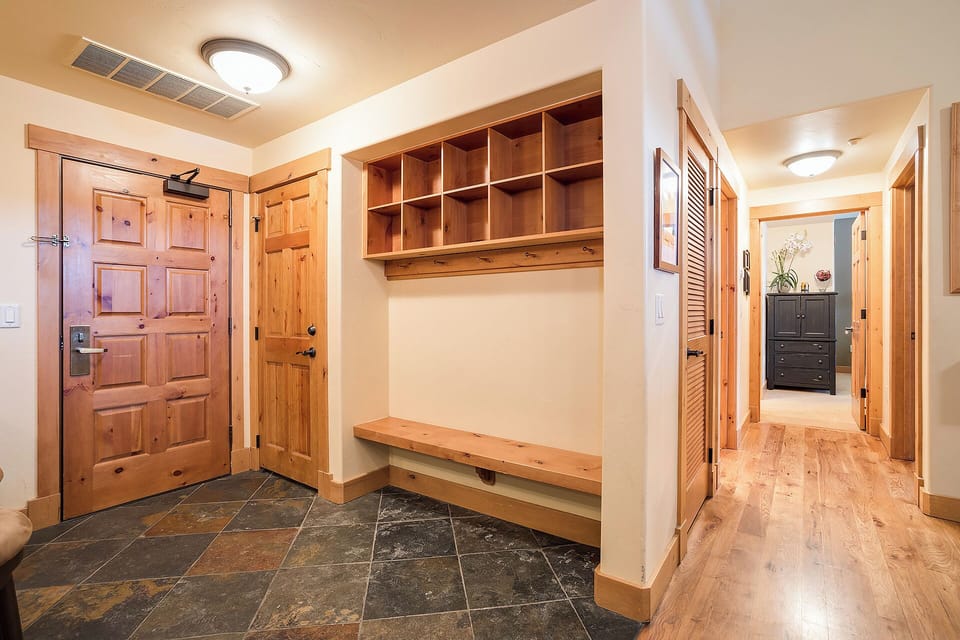 Step through the welcoming entrance into your mountain retreat, where custom wood cubbies and a built-in bench await to store your gear after a day of adventure, blending rustic warmth with thoughtful functionality.