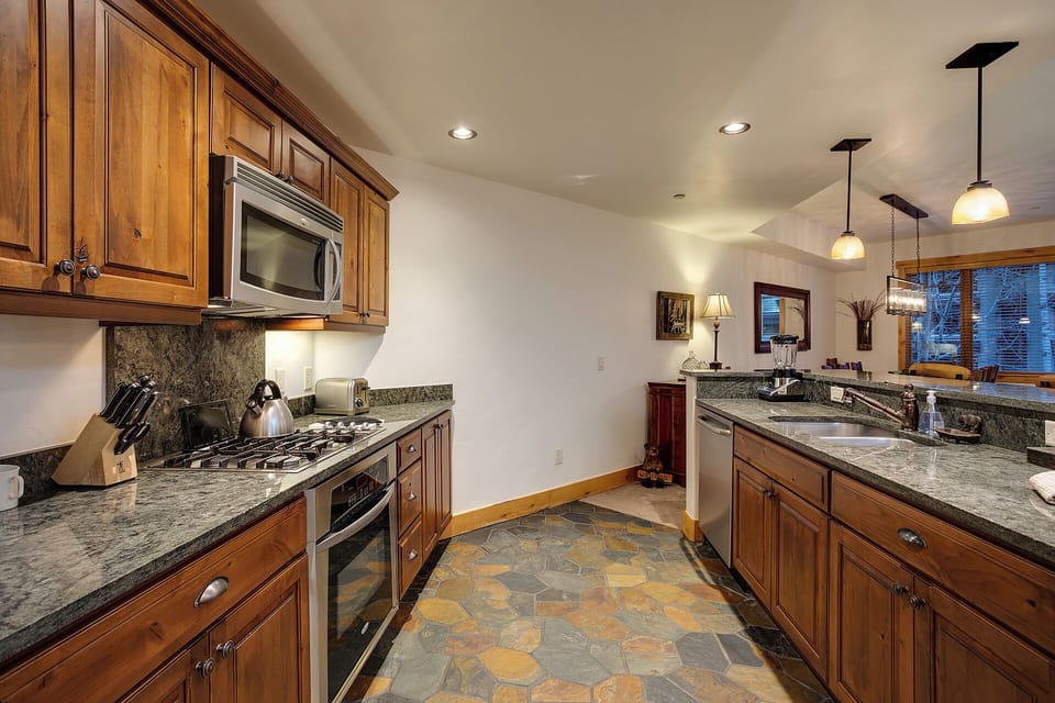 Your fully-equipped gourmet kitchen features granite counters, stainless appliances, and warm wood cabinetry—perfect for cooking meals together after a day of adventure.